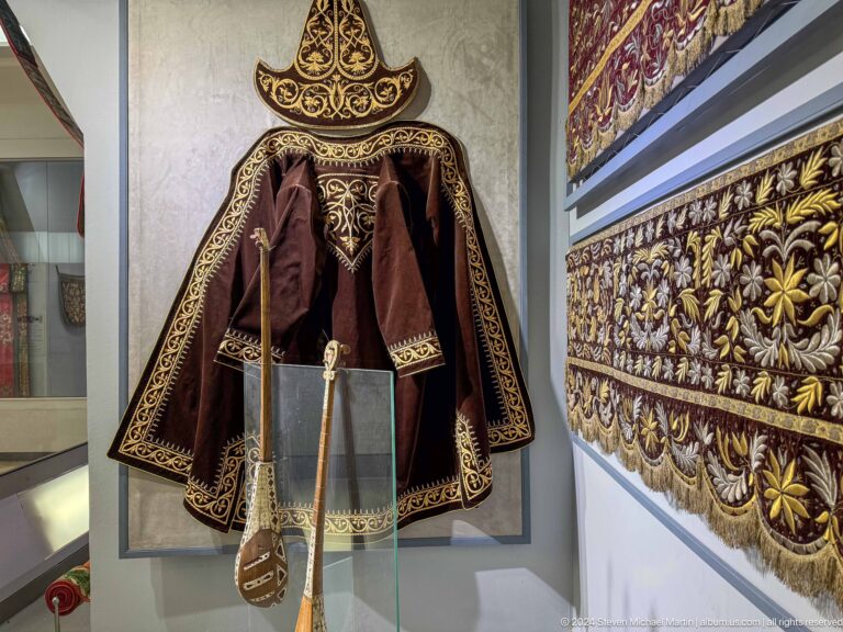 Dark traditional garment beside embroidered panel.
