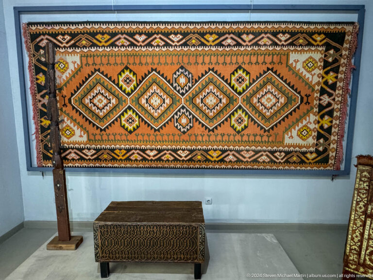 Large geometric carpet above wooden chest.