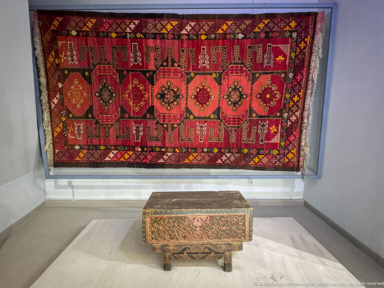 Red carpet with medallions above decorated chest.