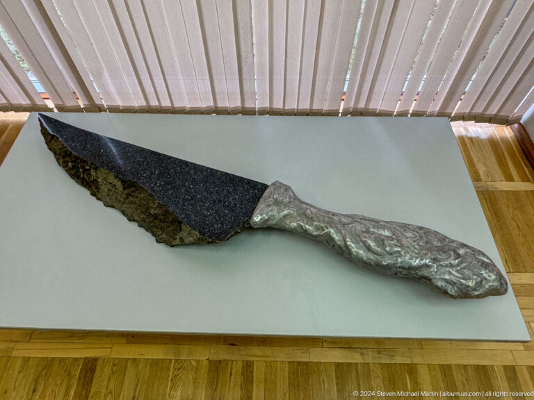 Elongated dark metal object in display case.