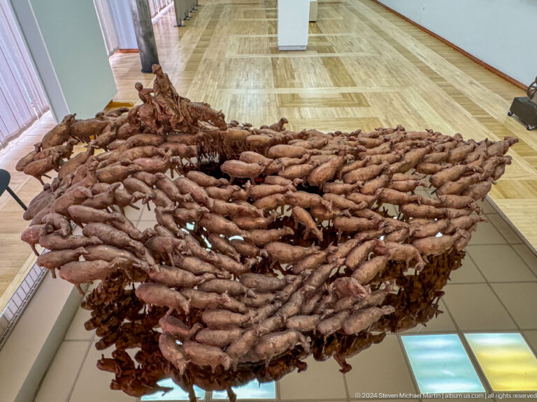 Suspended mass of many reddish carved elements.