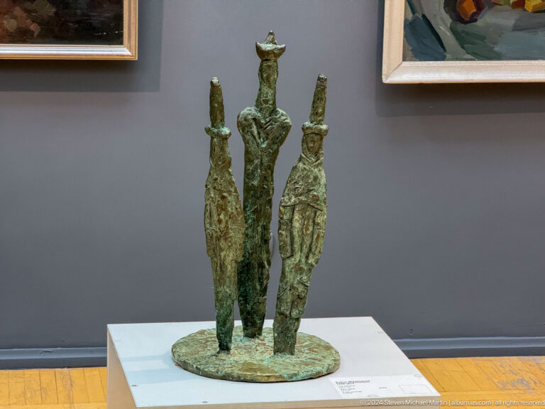 Three slender green bronze figures.