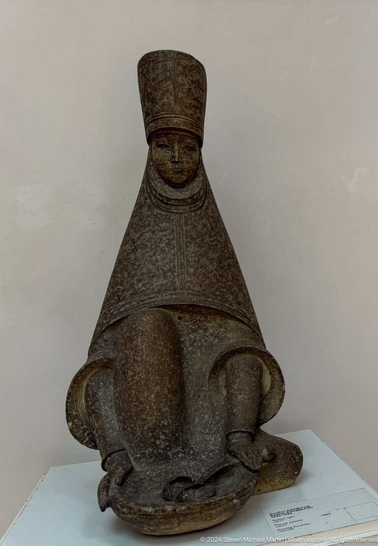 Close view of dark triangular sculpted face.