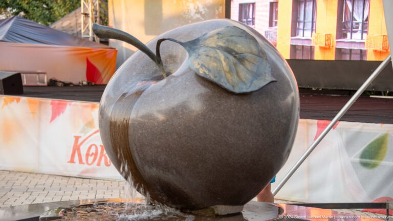 Polished stone apple sculpture with a metal leaf functioning as a fountain, spilling water into a basin at Kok Tobe in Almaty.