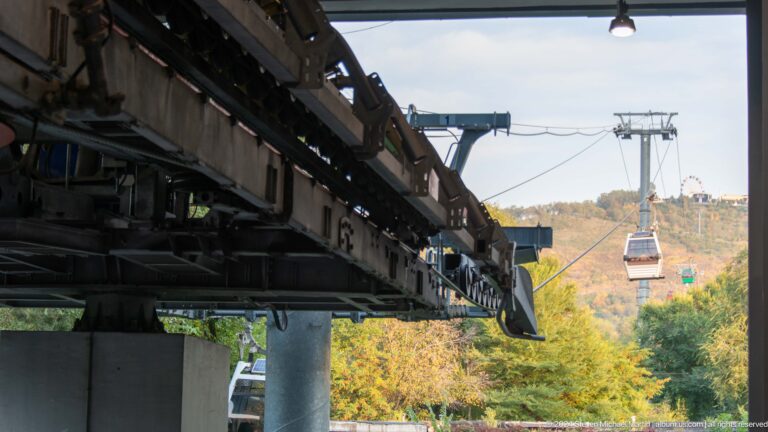 View from the Kok Tobe cable-car terminal showing steel track and pulley machinery with gondolas suspended over a wooded slope.