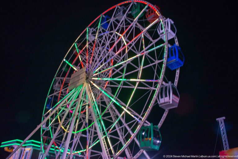 Illuminated Ferris wheel with multicolored lights at night at Kok Tobe, photographed from a low angle.