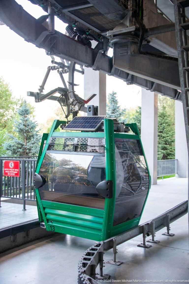 Green Kok Tobe cable-car cabin with rooftop solar panel at the station platform in Almaty.