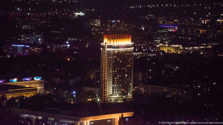 Brightly lit high-rise tower at night in central Almaty, seen from Kok Tobe.