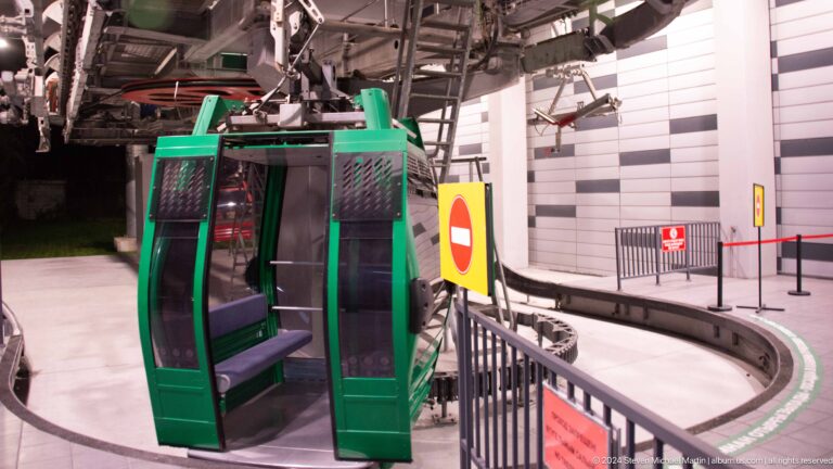 Open green cable-car cabin with doors wide at the Kok Tobe station platform.