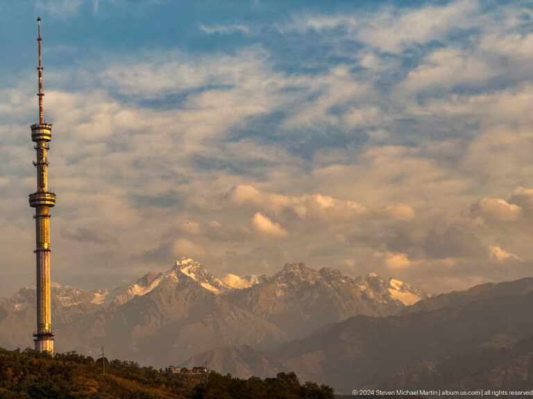 Almaty Television Tower at dusk with snow-covered Tian Shan mountains in the background, seen from Kok Tobe.