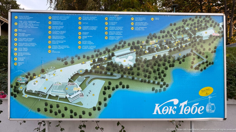 Illustrated Kok Tobe site map and attraction directory on a blue-background orientation panel.