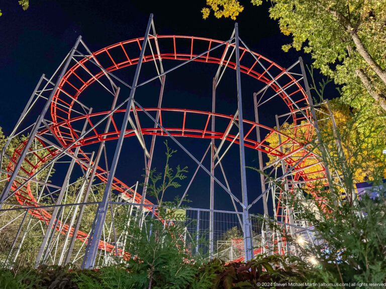 Small red roller-coaster track with gray steel supports at Kok Tobe, photographed at night.