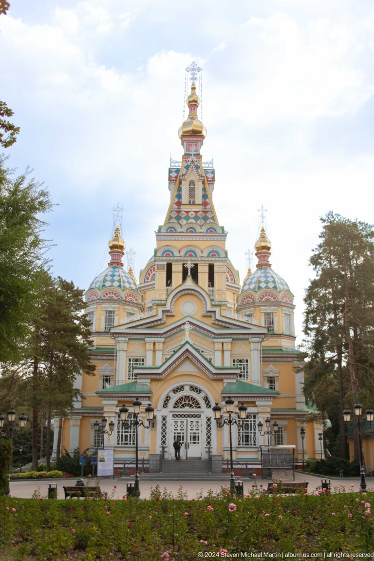 Daylight frontal view beneath overcast sky at the colorful wooden Zenkov Cathedral in Almaty.