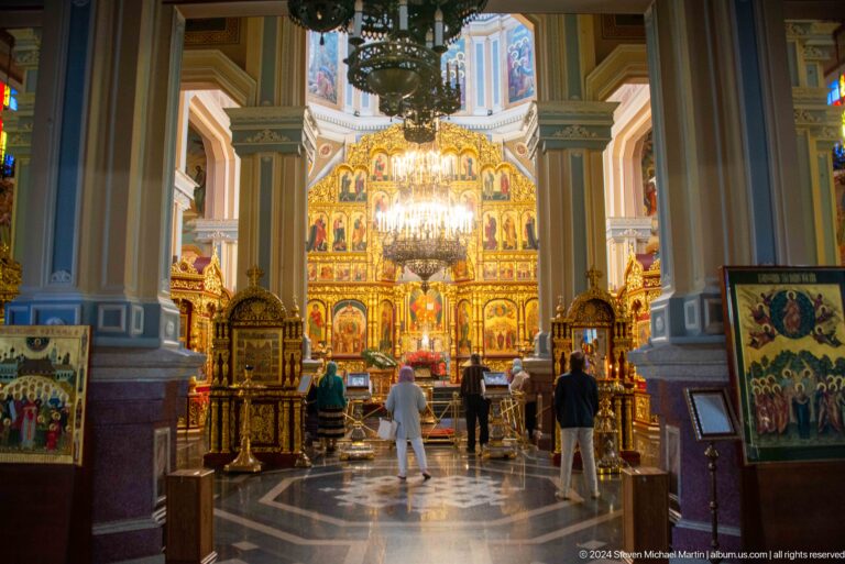 Wide nave with chandelier and iconostasis inside Zenkov Cathedral, with Orthodox religious decoration.