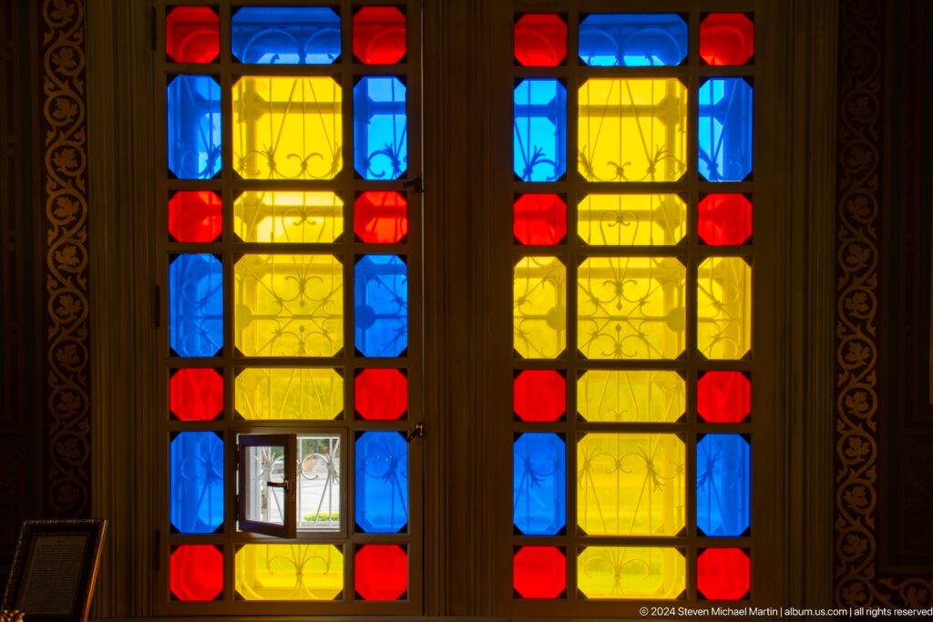 Geometric stained-glass windows inside Zenkov Cathedral, with Orthodox religious decoration.