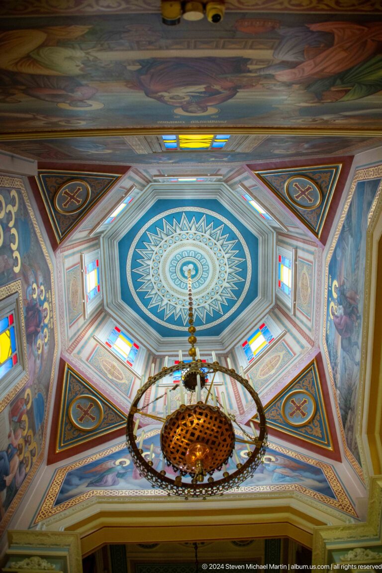 Blue octagonal dome ceiling and chandelier at the colorful wooden Zenkov Cathedral in Almaty.