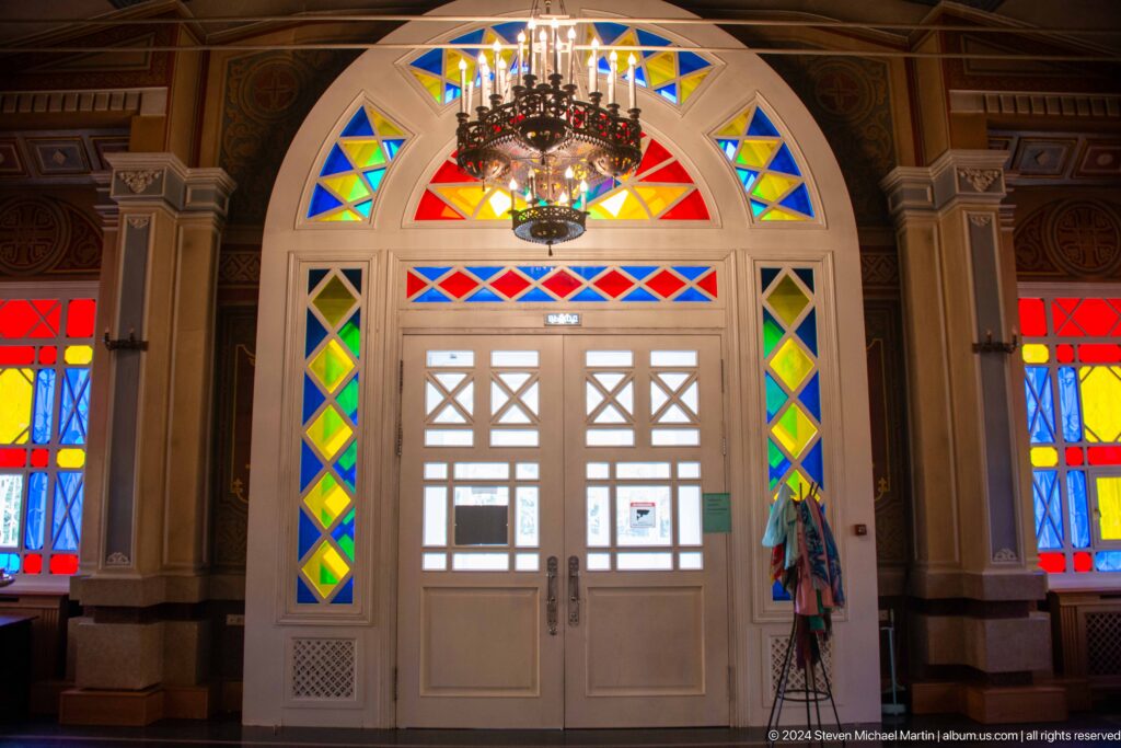 Arched entrance with stained glass inside Zenkov Cathedral, with Orthodox religious decoration.
