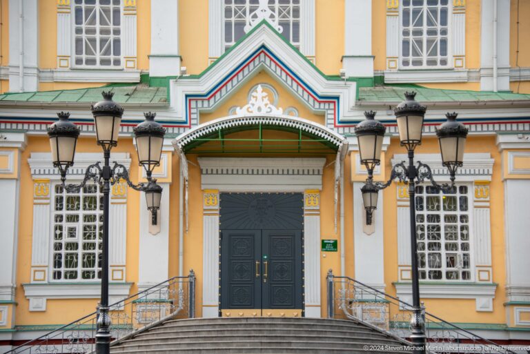 Green side door beneath decorative porch at the colorful wooden Zenkov Cathedral in Almaty.