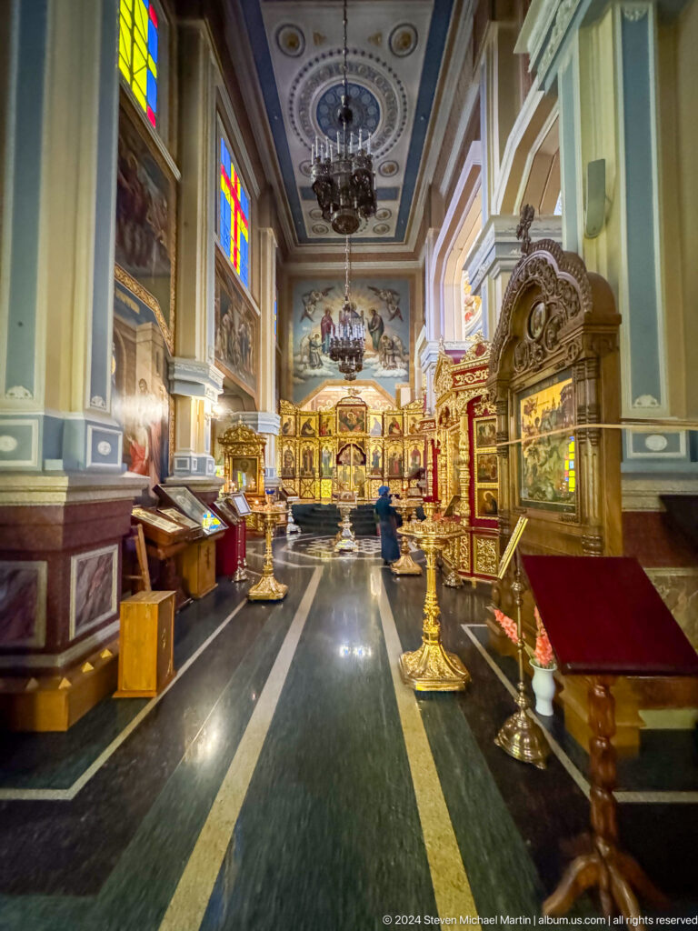 Side aisle lined with icons inside Zenkov Cathedral, with Orthodox religious decoration.