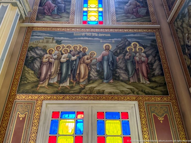 Mural of apostles above stained glass inside Zenkov Cathedral, with Orthodox religious decoration.