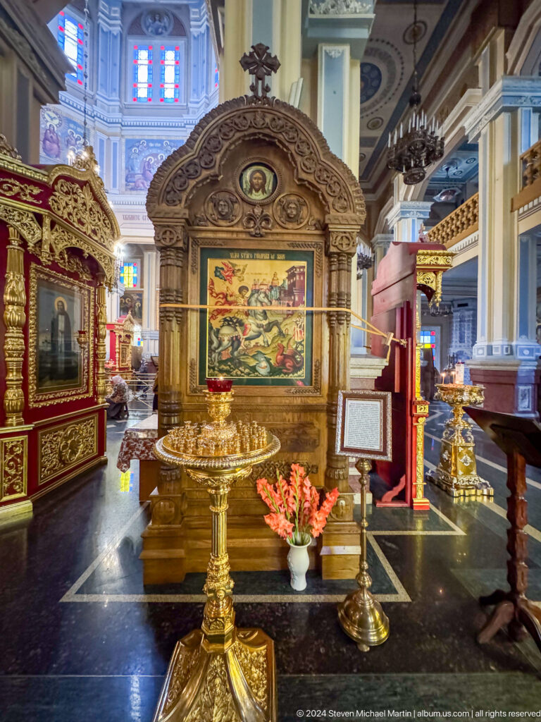 Gilded icon stand and flower arrangement inside Zenkov Cathedral, with Orthodox religious decoration.