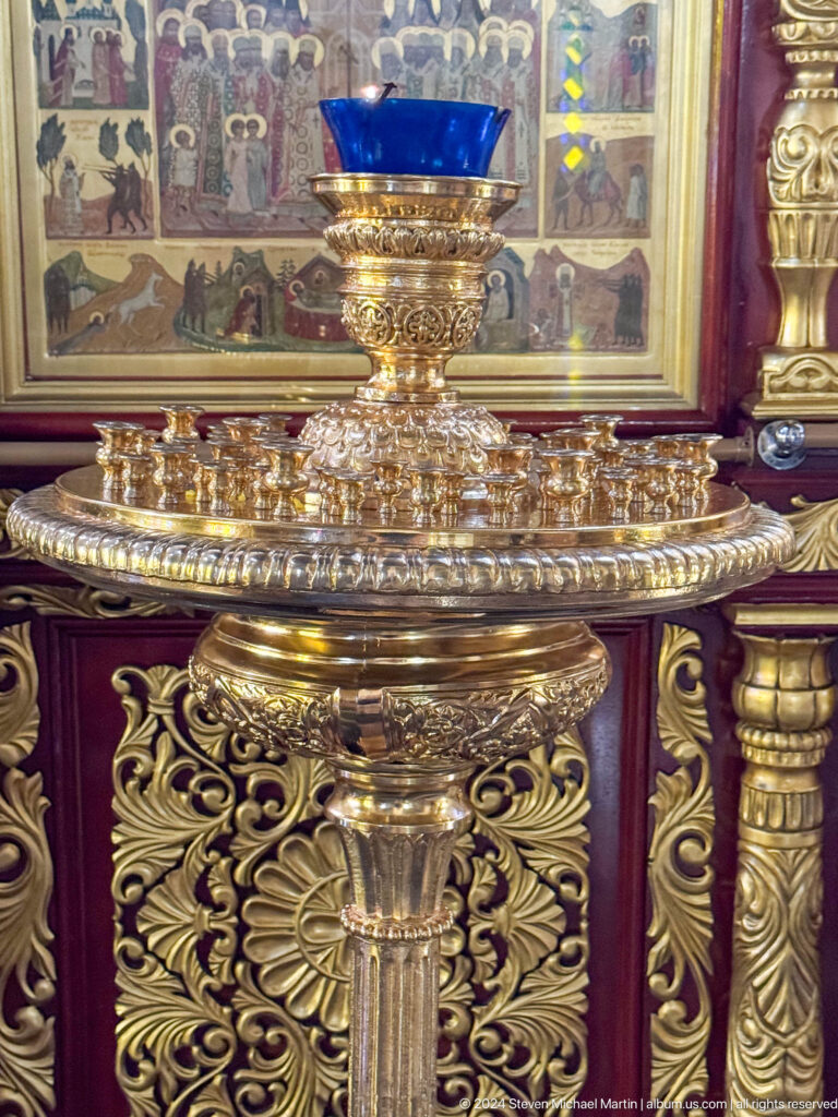 Ornate brass candle basin inside Zenkov Cathedral, with Orthodox religious decoration.
