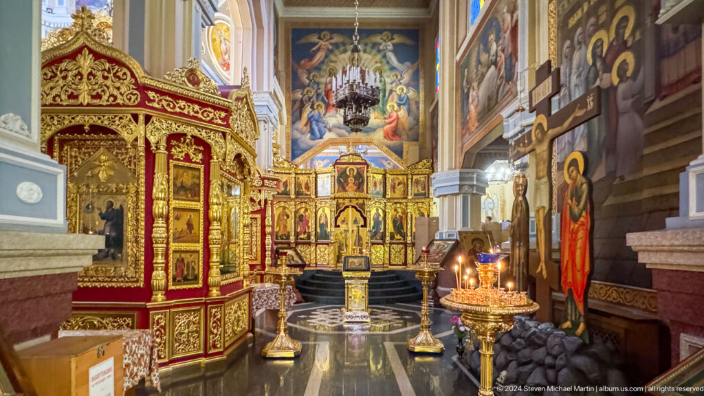 Interior toward iconostasis with candles inside Zenkov Cathedral, with Orthodox religious decoration.