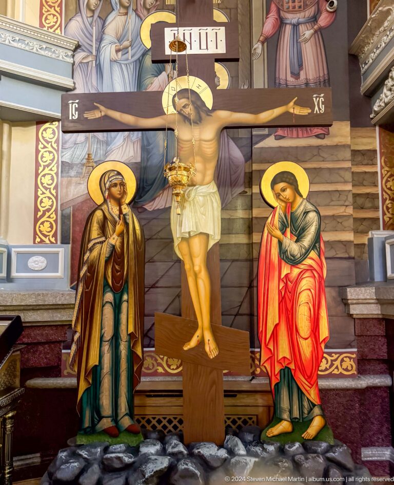 Crucifixion mural with flanking saints inside Zenkov Cathedral, with Orthodox religious decoration.