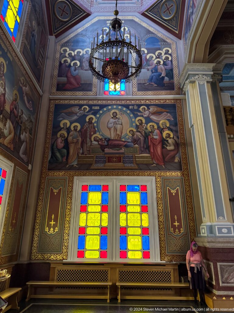 Upper mural above stained glass inside Zenkov Cathedral, with Orthodox religious decoration.