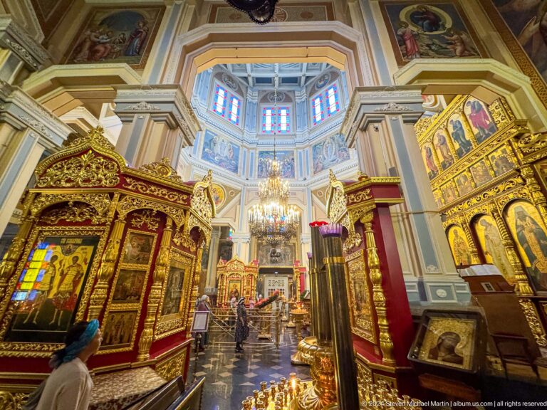 Nave view beneath chandelier inside Zenkov Cathedral, with Orthodox religious decoration.