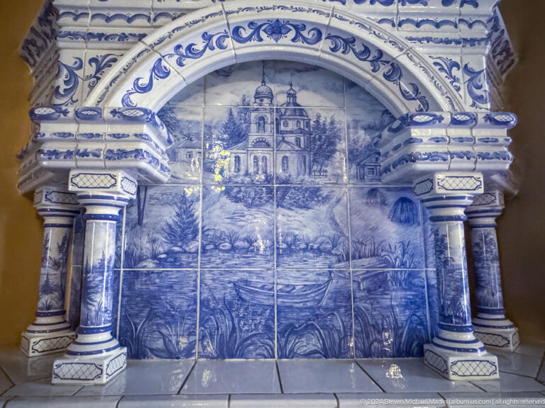 Second view of blue tiled memorial inside Zenkov Cathedral, with Orthodox religious decoration.
