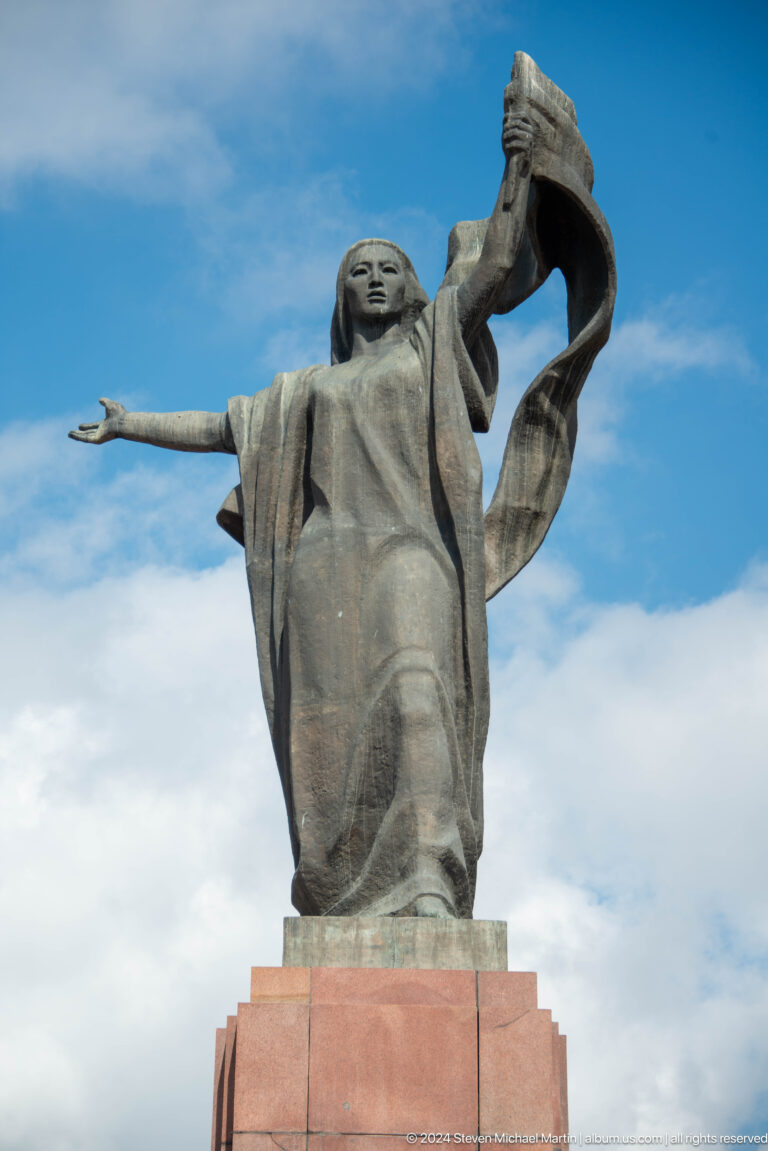 Monumental bronze woman with raised arm in Bishkek, Kyrgyzstan.