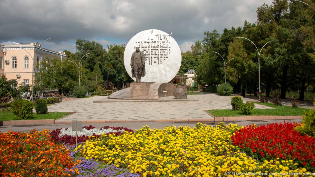 Circular memorial with flowers in foreground in Bishkek, Kyrgyzstan.