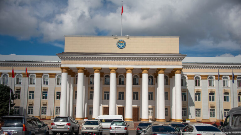Columned government building under dramatic clouds in Bishkek, Kyrgyzstan.