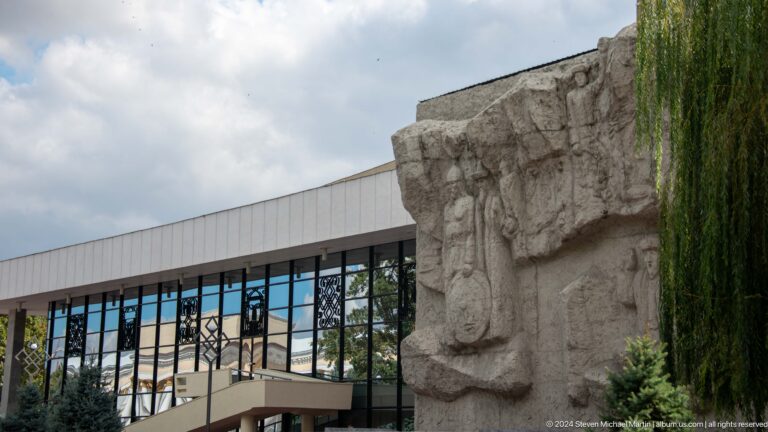 Stone relief beside glass-fronted cultural building in Bishkek, Kyrgyzstan.