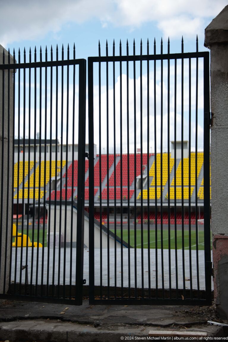 Empty stadium seen through vertical fence in Bishkek, Kyrgyzstan.