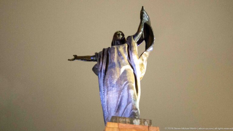 Woman holding raised flag in monumental sculpture in Bishkek, Kyrgyzstan.