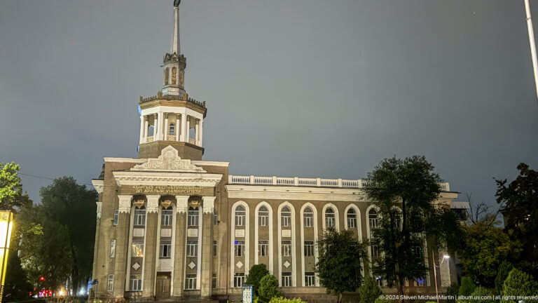 Towered neoclassical building illuminated at night in Bishkek, Kyrgyzstan.