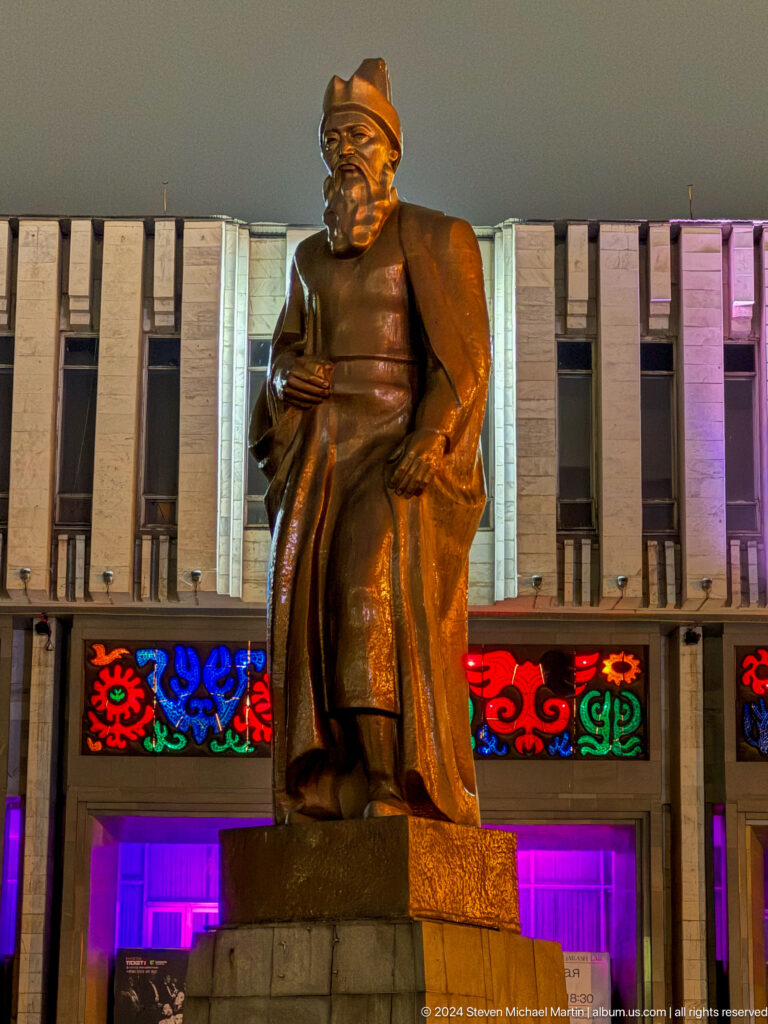 Bronze statue lower body before textile panels in Bishkek, Kyrgyzstan.