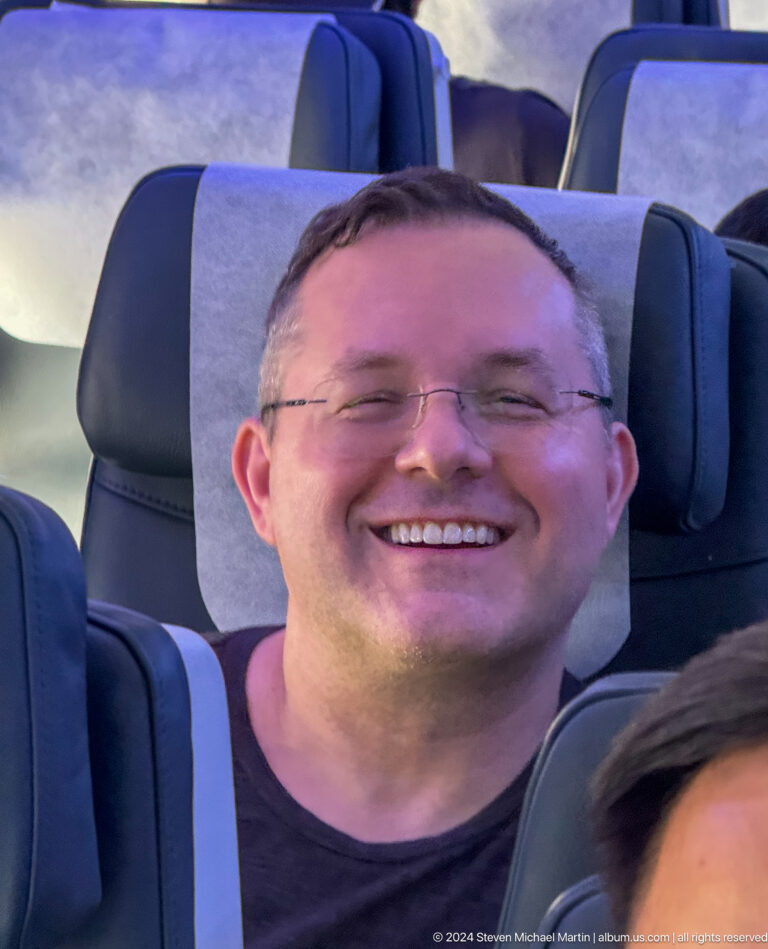 Smiling man seated inside an aircraft cabin in Bishkek, Kyrgyzstan.
