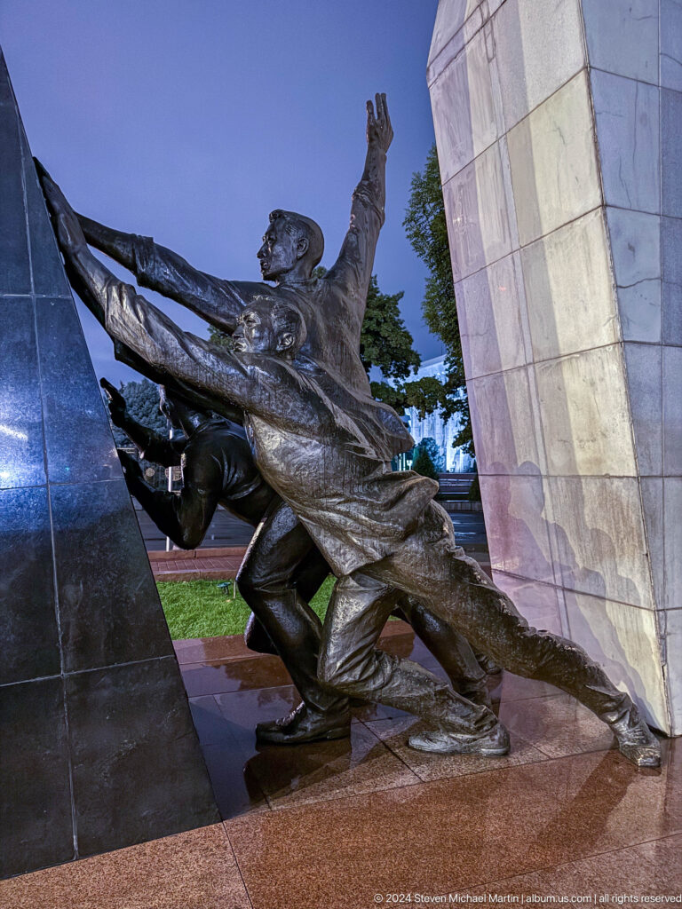Bronze wartime figures beside memorial wall in Bishkek, Kyrgyzstan.