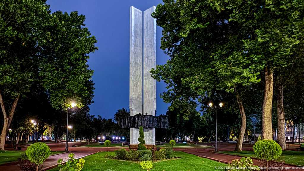 Tall memorial obelisk framed by trees in Bishkek, Kyrgyzstan.