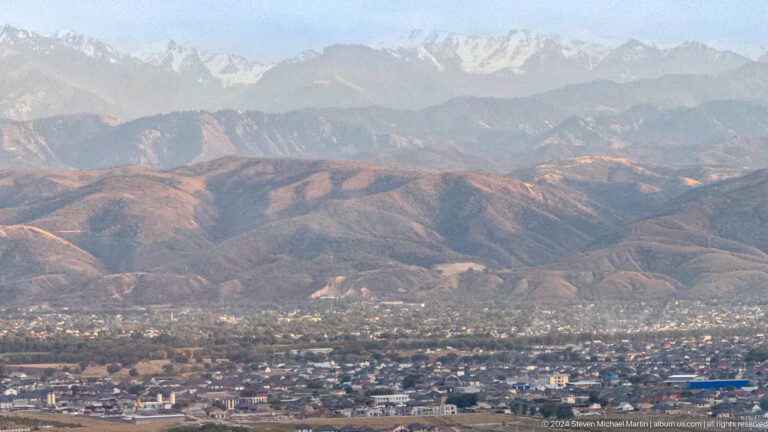 City spread across foothills below snowy mountains in Bishkek, Kyrgyzstan.