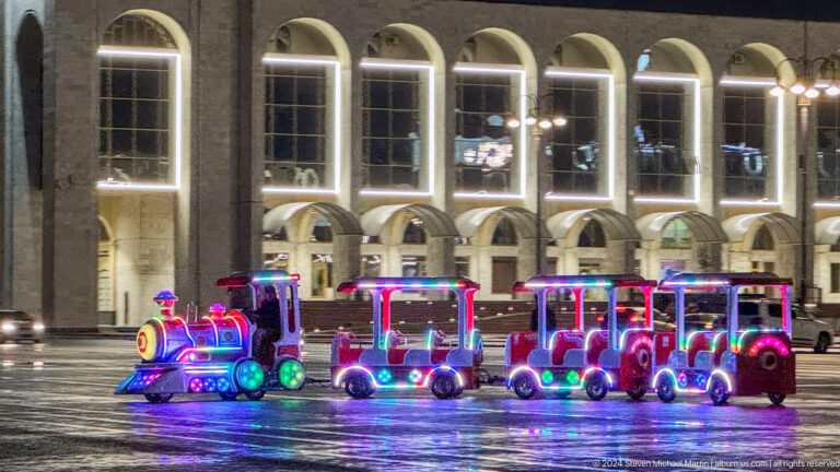 Colorful children’s train on wet square in Bishkek, Kyrgyzstan.