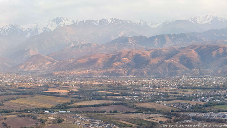 Sunlit city and reddish foothills from above in Bishkek, Kyrgyzstan.