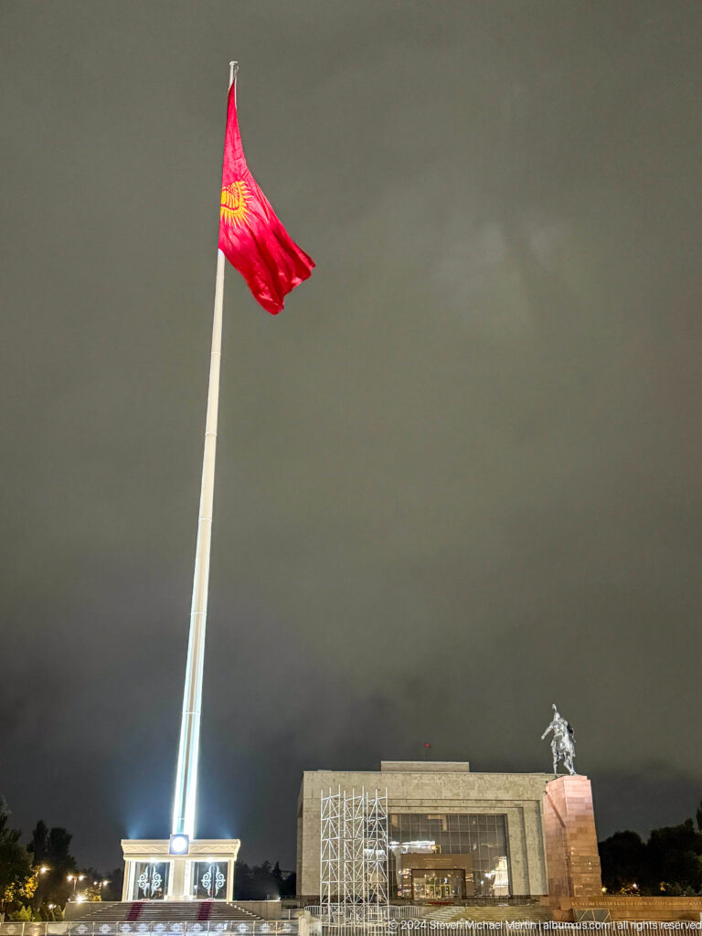 Kyrgyz flag on tall pole against dark sky in Bishkek, Kyrgyzstan.
