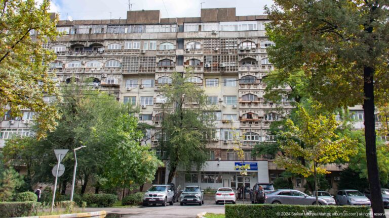 Soviet apartment block behind trees in Bishkek, Kyrgyzstan.