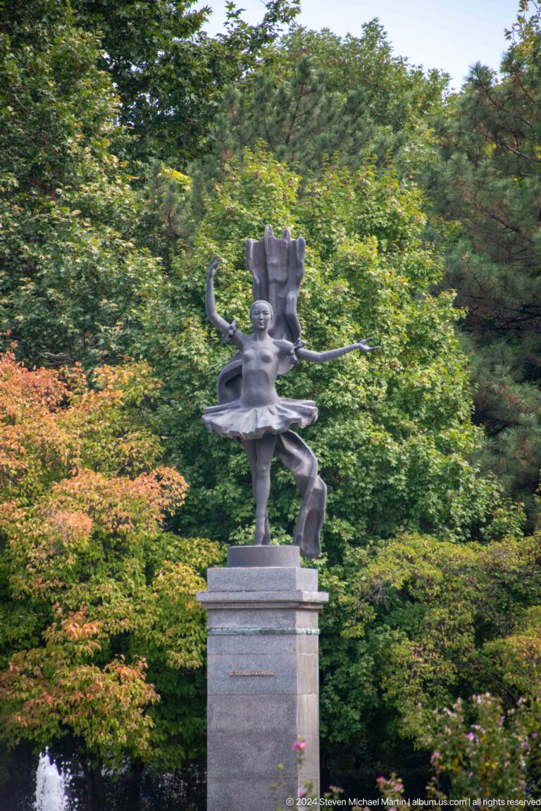 Bronze ballerina posed in leafy park in Bishkek, Kyrgyzstan.