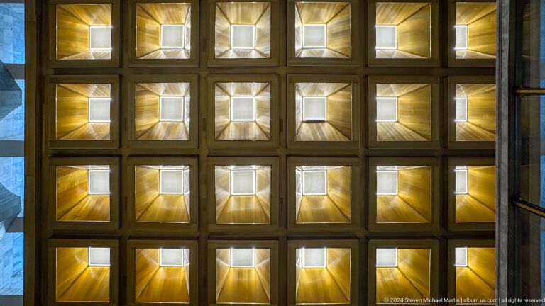 Geometric grid of glowing square ceiling coffers.