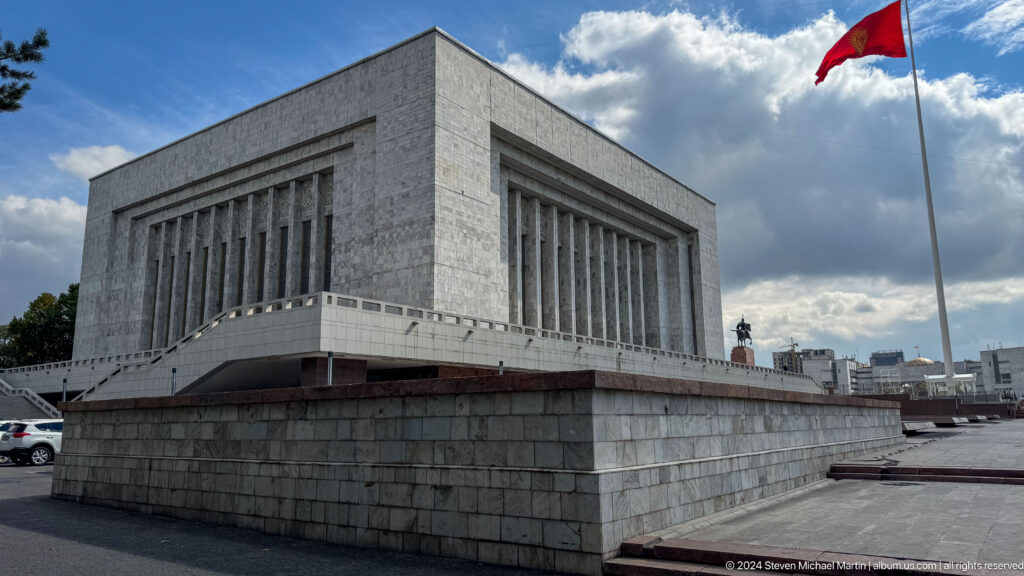 White-stone museum exterior beneath Kyrgyz flag.